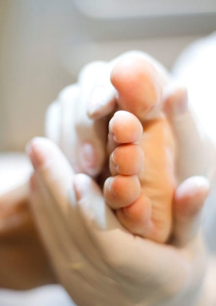 Pé apoiado nas mãos com luva antes do procedimento